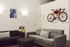 a living room with a couch and a bike on the wall at Cozy Queen Street 1 Bedroom flat in the Heart of Central Business District in Auckland