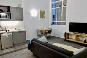 a living room with a couch and a kitchen at Cozy Queen Street 1 Bedroom flat in the Heart of Central Business District in Auckland