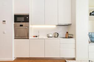 uma cozinha branca com armários e electrodomésticos brancos em Spacious Studio in Lisbon em Lisboa