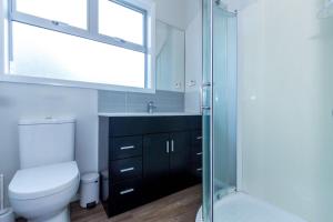 a bathroom with a toilet and a glass shower at Sunny Character 2 Bedroom Home - Mission Bay in Auckland
