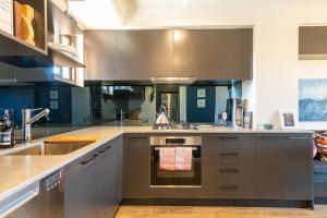 a kitchen with gray cabinets and a sink at Modern 1 Bedroom Apartment In The Italian Forum in Sydney