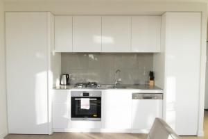 a white kitchen with a stove and a sink at Brand New 1 Bedroom Apartment in South Melbourne in Melbourne
