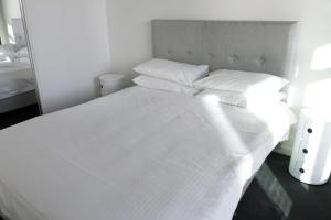 a white bed with white sheets and pillows at Brand New 1 Bedroom Apartment in South Melbourne in Melbourne