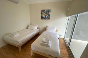 two beds in a small room with a window at Stunning Two-Storey Apartment in Perth's CBD in Perth