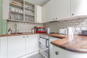una cucina con armadi bianchi e piano di lavoro di Modern 2 Bedroom flat in Central London a Londra