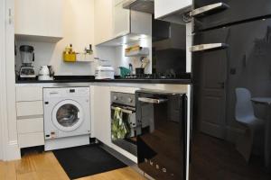a kitchen with a washing machine and a washer and dryer at Bright and Modern 1 Bed Flat in Highbury in London