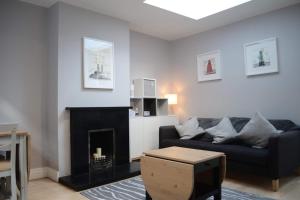 a living room with a black couch and a fireplace at Charming 2 Bedroom Cottage in Central Location in Dublin