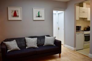 a living room with a blue couch and a kitchen at Charming 2 Bedroom Cottage in Central Location in Dublin