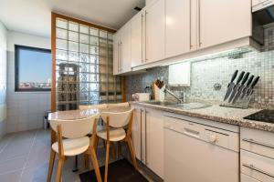 リスボンにあるModern 2 Bedroom Apartment with Balcony and Amazing Viewsの白いキャビネット、テーブルと椅子付きのキッチンが備わります。