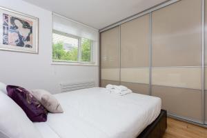 ロンドンにあるLovely 1 Bedroom Apartment with Balcony in Putneyの白いベッドルーム(大型ベッド1台、窓付)