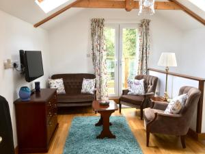 a living room with a tv and a couch and chairs at Meander in Penzance
