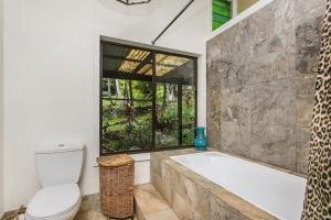 a bathroom with a tub and a toilet and a window at The Jewel of the Valley in Goonengerry