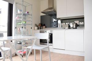 a kitchen with white cabinets and a table and chairs at Bright 1 Bedroom Flat in North London With Balcony in London