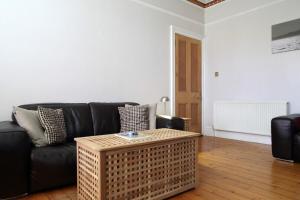 a living room with a black couch and a coffee table at Central and Spacious 2 Bedroom Flat With Garden in Edinburgh