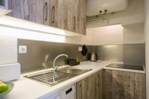 a kitchen with a sink and wooden cabinets at Sunny photographers Studio Apartment with Balcony in Alcântara in Lisbon