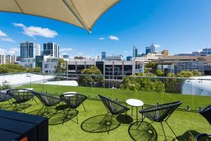 a group of chairs and tables on a balcony with a city skyline at Chic Apartment with Rooftop in Perth