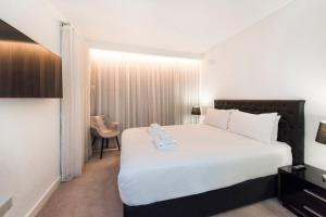 a bedroom with a large white bed and a chair at Chic Apartment with Rooftop in Perth