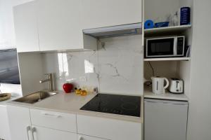a white kitchen with a sink and a microwave at Cute Studio Apartment in Maroubra in Sydney