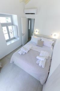 a white bedroom with a white bed with towels on it at La Maison de Marie Geraldine in Hydra