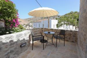 a patio with a table and chairs and an umbrella at La Maison de Marie Geraldine in Hydra