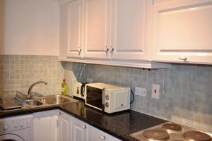 een keuken met witte kasten en een magnetron bij 2 Bedroom Apartment near historical Christchurch in Dublin
