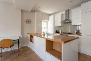 a kitchen with white cabinets and a wooden counter top at Fantastic 2 Bedroom Apartment in Central London in London