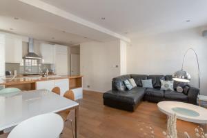 a living room with a black leather couch and a kitchen at Fantastic 2 Bedroom Apartment in Central London in London