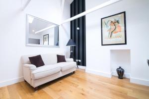 een woonkamer met een witte bank en een spiegel bij Contemporary 1 Bed Flat in Fulham Near The Thames in Londen