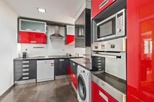 una cucina con elettrodomestici e armadietti rossi e bianchi di Stunning 2 Bedroom Apartment near Belém a Lisbona