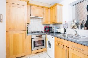 a kitchen with wooden cabinets and a sink and a dishwasher at 1 Bedroom Apartment on The Riverbank Near St Paul's in London