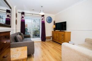 ein Wohnzimmer mit einem Sofa und einem TV in der Unterkunft 1 Bedroom Apartment on The Riverbank Near St Paul's in London