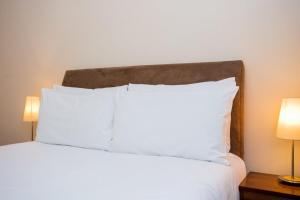 a white bed with white pillows and two lamps at 1 Bedroom Apartment on The Riverbank Near St Paul's in London