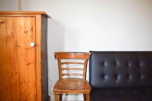 a wooden chair sitting next to a black couch at 1 Bedroom Apartment With Incredible Location in Sydney