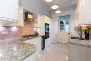 a large kitchen with white cabinets and granite counter tops at Beautifully Modernised New Town Home in Edinburgh