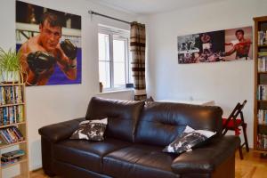 a living room with a brown leather couch and posters at Charming Cosy Coach House in Fishponds Bristol in Bristol