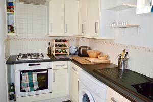 La cuisine est équipée de placards blancs et d'un four avec plaques de cuisson. dans l'établissement Charming Cosy Coach House in Fishponds Bristol, à Bristol