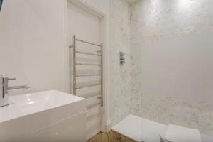 a white bathroom with a sink and a shower at Elegant 1 Bedroom Apartment in South Kensington in London