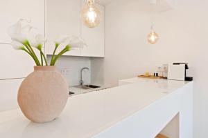 a white kitchen with a vase with flowers on a counter at Modern Portuguese 1 Bedroom Apartment in Belém in Lisbon