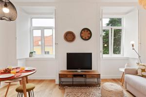 Una sala de estar con un televisor y una mesa. en Modern Portuguese 1 Bedroom Apartment in Belém, en Lisboa
