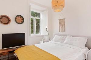 Un dormitorio con una cama y un televisor de pantalla plana. en Modern Portuguese 1 Bedroom Apartment in Belém, en Lisboa