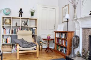 a living room with a chair and a book shelf at Classic Edinburgh Flat in the heart of Morningside in Edinburgh