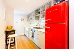 a red refrigerator in a kitchen with white cabinets at Beautifully Styled Modern Apartment With Garden in London