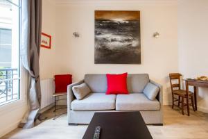 sala de estar con sofá y almohada roja en Modern arty flat close to Saint-Germain des Près, en París