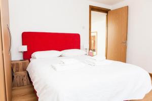 a bedroom with a large white bed with a red headboard at Spectacular Central 4-Bedroom Close To London Eye in London
