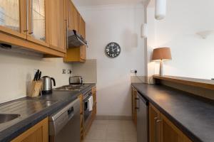 a kitchen with wooden cabinets and a clock on the wall at Bright and Spacious 1 Bedroom Apartment in the Heart of Kensington in London