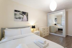 1 dormitorio con 1 cama blanca grande y espejo en Stylish and Homely 4 Bedroom Home in East London en Londres