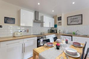 una cocina con armarios blancos y una mesa con platos. en Stylish and Homely 4 Bedroom Home in East London en Londres