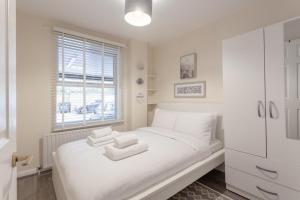 Un dormitorio blanco con una cama con toallas. en Stylish and Homely 4 Bedroom Home in East London en Londres