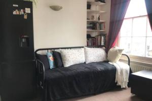 una camera da letto con letto, cuscini e finestra di Lovely Victorian Flat for 6 in Stoke Newington a Londra