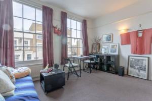 un soggiorno con divano, tavolo e finestra di Lovely Victorian Flat for 6 in Stoke Newington a Londra
